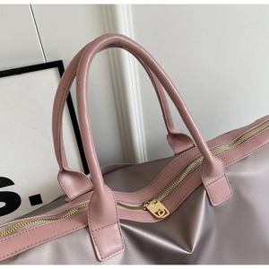 Gros plan du sac de voyage montrant les fermetures éclair et les finitions en cuir rose