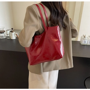 Detail of red glossy tote bag with leather texture shown on a female model
