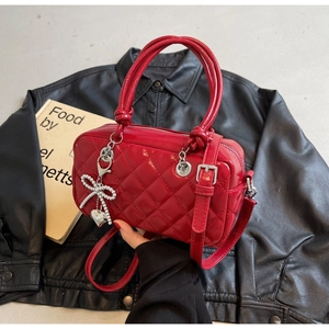 Detail of red quilted square handbag with pearl butterfly heart charm and silver hardware