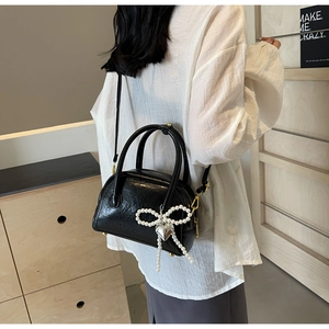 Détail du sac en cuir froissé noir avec grand nœud en perles et pendentif cœur argenté
