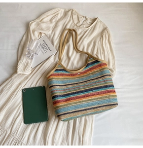 Detail of colorful striped straw tote bag featuring woven texture and silver magnetic closure