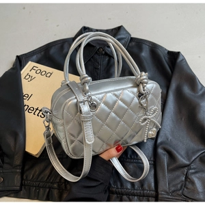 Silver metallic quilted handbag with knot handles and pearl bow charm on black leather