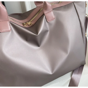 Détail du sac de voyage rose en nylon avec texture satinée et fermetures éclair dorées