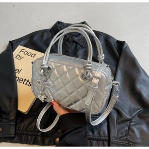 Close-up of silver quilted crossbody bag with rhinestone heart and bow charms