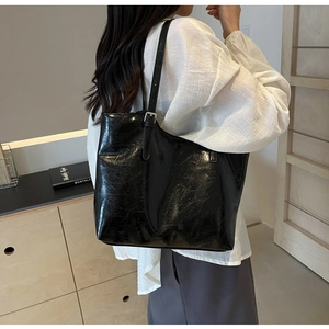 Detail of crinkled black leather tote bag featuring adjustable silver buckle strap