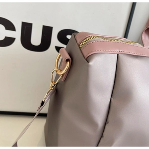 Gros plan du sac de voyage lilas avec ferrures dorées et détails de couture soignés
