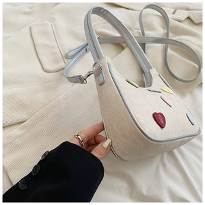 Detailed close-up of a crescent-shaped crossbody bag with colorful heart patches and strap