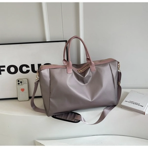 Détails du grand sac de voyage gris-mauve avec poignées en cuir rose et fermetures éclair dorées