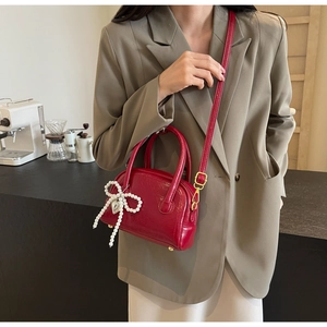 Sac à main rouge brillant avec pendentif nœud en perles dans un cadre lifestyle chic