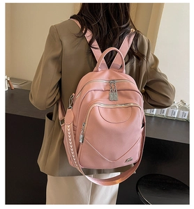 Détail d'un sac à dos en cuir grainé rose avec fermetures éclair et bretelles tissées