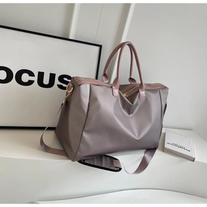 Détails du tissu en nylon haute densité et accessoires dorés sur le sac de voyage rose