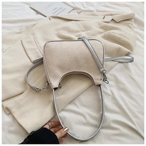 Close-up of beige canvas and silver leather texture on a modern saddle bag