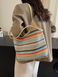 Large colorful striped straw tote bag worn over shoulder for beach and summer travel