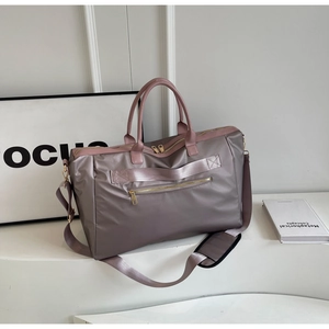 Détail du sac de voyage mauve avec fermetures dorées et bandoulière ajustable
