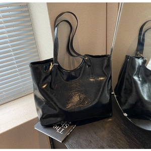 Macro shot of glossy black patent leather texture on a spacious tote bag with shoulder straps