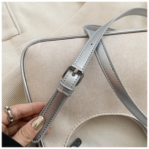 Detail view of adjustable silver shoulder strap with metal buckle on fashion handbag