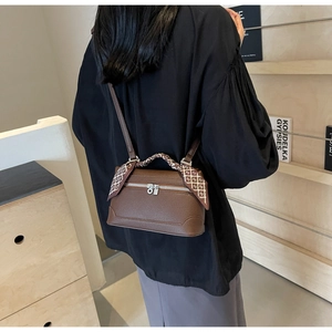 Detailed macro view of dark brown pebbled leather handbag featuring a silk scarf-wrapped handle