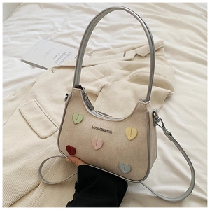 Detail of hobo bag featuring colorful heart patches and premium suede-like texture