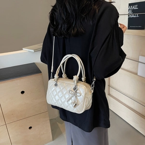 Quilted cream crossbody bag with silver heart charms and dual handles on a model