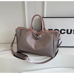 Détail d'un grand sac de voyage en nylon rose avec ferrures dorées et bandoulière