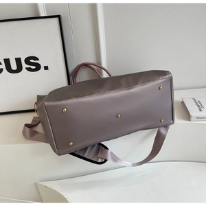 Détail du fond du sac de voyage avec cinq pieds en métal doré et nylon satiné