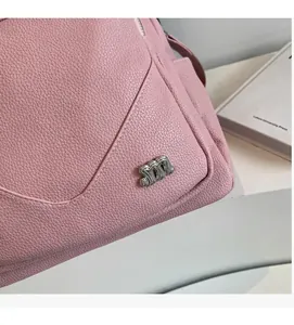 Détail d'un sac à dos en cuir rose grainé avec logo M métallique argenté brillant