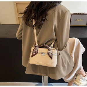 Detail of a cream textured leather box bag with a silk scarf handle and silver hardware