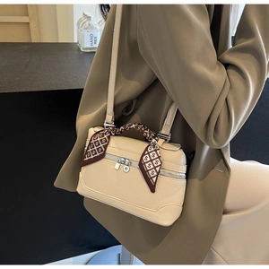 Detail of cream lychee leather handbag with decorative silk scarf on the handle