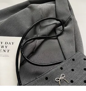 Détail du sac en toile grise à pois noirs avec pendentif nœud papillon argenté