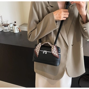 Detail view of a black pebble leather crossbody bag with a silk scarf wrapped handle