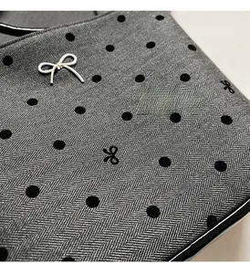 Détail du tissu à chevrons gris avec pois noirs et décoration de nœud en métal argenté