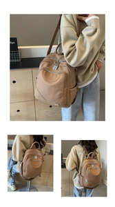 Détail de sac à dos en cuir kaki avec zips argentés et bandoulière géométrique