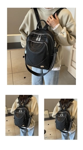 Gros plan du sac à dos en cuir grainé noir avec logo doré et détails zippés élégants