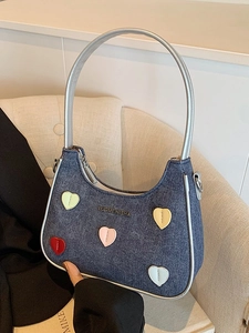 Denim underarm bag with silver leather trim and colorful heart patches on the front