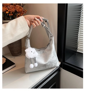 Detail view of silver metallic bag featuring a cute white cloud pendant and zip closure