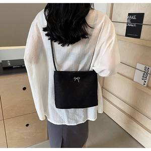 Détail du sac bandoulière noir avec nœud métallique et motif monogramme gaufré