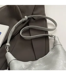 Close-up of a silver hobo bag with adjustable strap on a dark brown blazer jacket