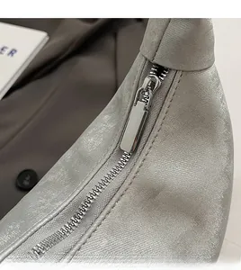 Detail shot of the smooth metal zipper and textured silver fabric of the dumpling bag