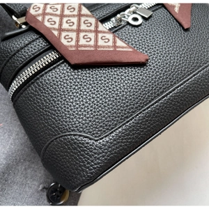 Close-up of black lychee leather texture with silver zipper and patterned silk scarf