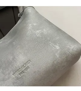 Detailed close-up of the silver grey textured fabric with embossed logo on the dumpling bag