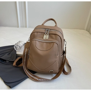 Détail d'un sac à dos en cuir marron avec bandoulière à motifs sur fond de tissu blanc