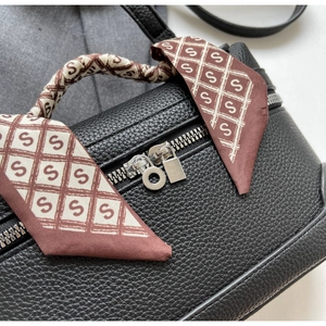 Detail of black lychee leather bag with silver zipper and silk scarf wrapped on handle