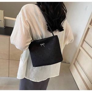 Vue détaillée d'un sac cabas noir en toile avec nœud blanc porté par un mannequin femme