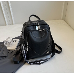 Détail du sac à dos en cuir grainé noir avec une large bandoulière tissée à motif géométrique