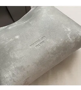 Close-up of silver-grey PU leather texture with MINGDAILANDI embossed logo on the bag