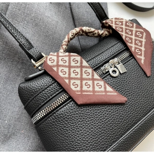 Detail of black lychee leather bag with elegant printed silk scarf wrapped on handle
