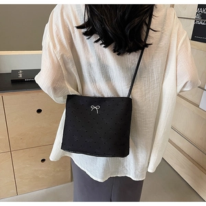 Vue détaillée du sac seau en toile noire avec nœuds argentés et motifs discrets gravés