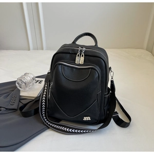 Détail du sac à dos en cuir noir avec logo en métal et large bandoulière tissée