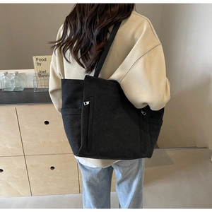 Detail of black canvas tote bag showing side pockets and vertical zipper compartment
