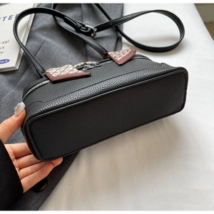 Detail of black lychee grain leather shoulder bag with side plaid fabric accents